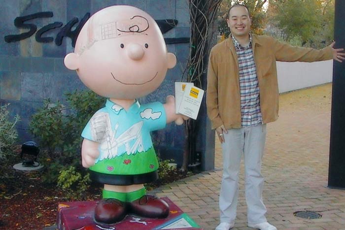 Aritst Marten Go standing next to large human scale Charlie Brown at the Peanuts Museum in Santa Rosa, California