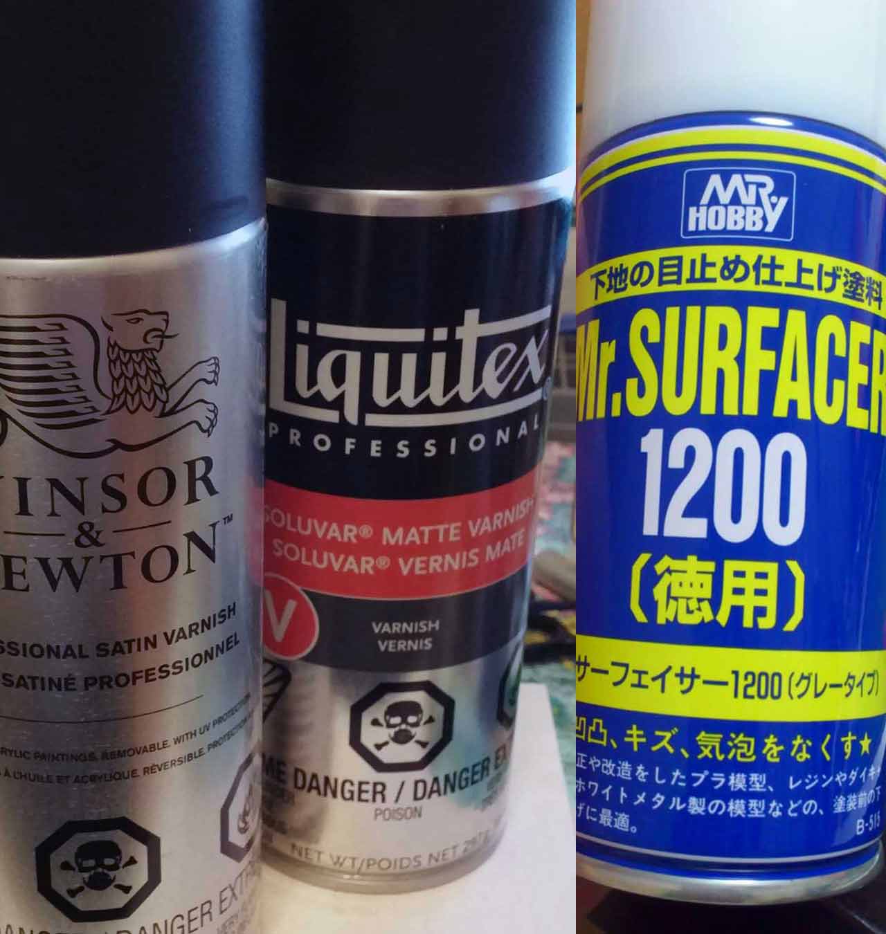 Winsor Newton Satin Varnish Aerosol, Liquitex Professionla Matte Varnish aerosol and Mr. Surfacer 1200 by Mr. Hobby Gunze on desk