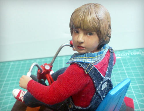 Danny Lloyd as Danny Torrance in the Stephen King novel adapted by Stanley Kubrick looking back over shoulder seated on big wheel statue by Marten Go aka MGO