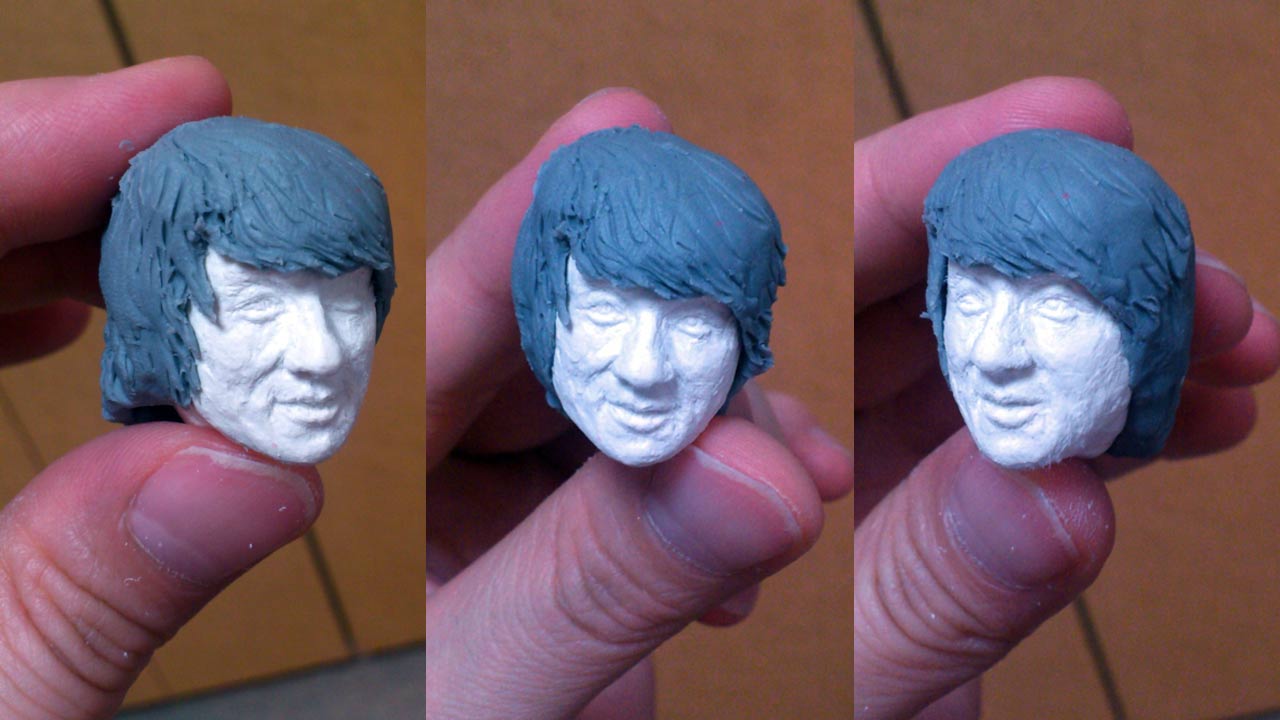 Three close up images side by side by side of the miniature refined sculpted head of Thomas with pronounced facial details and stand-in hair